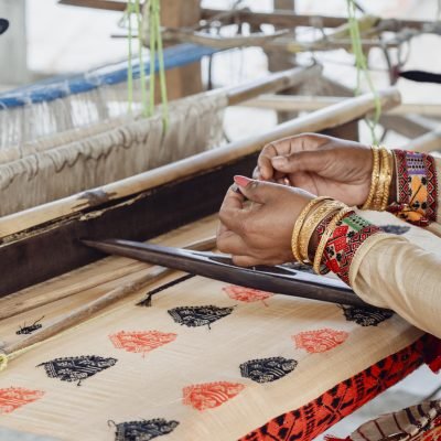 Woman weaving muga silk mekehla sador on a traditional handloom
